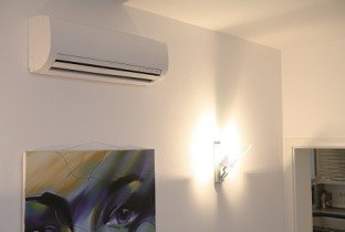 Nástěnná klimatizace Toshiba v interiéru nad obrazem a nástěnným osvětlením
